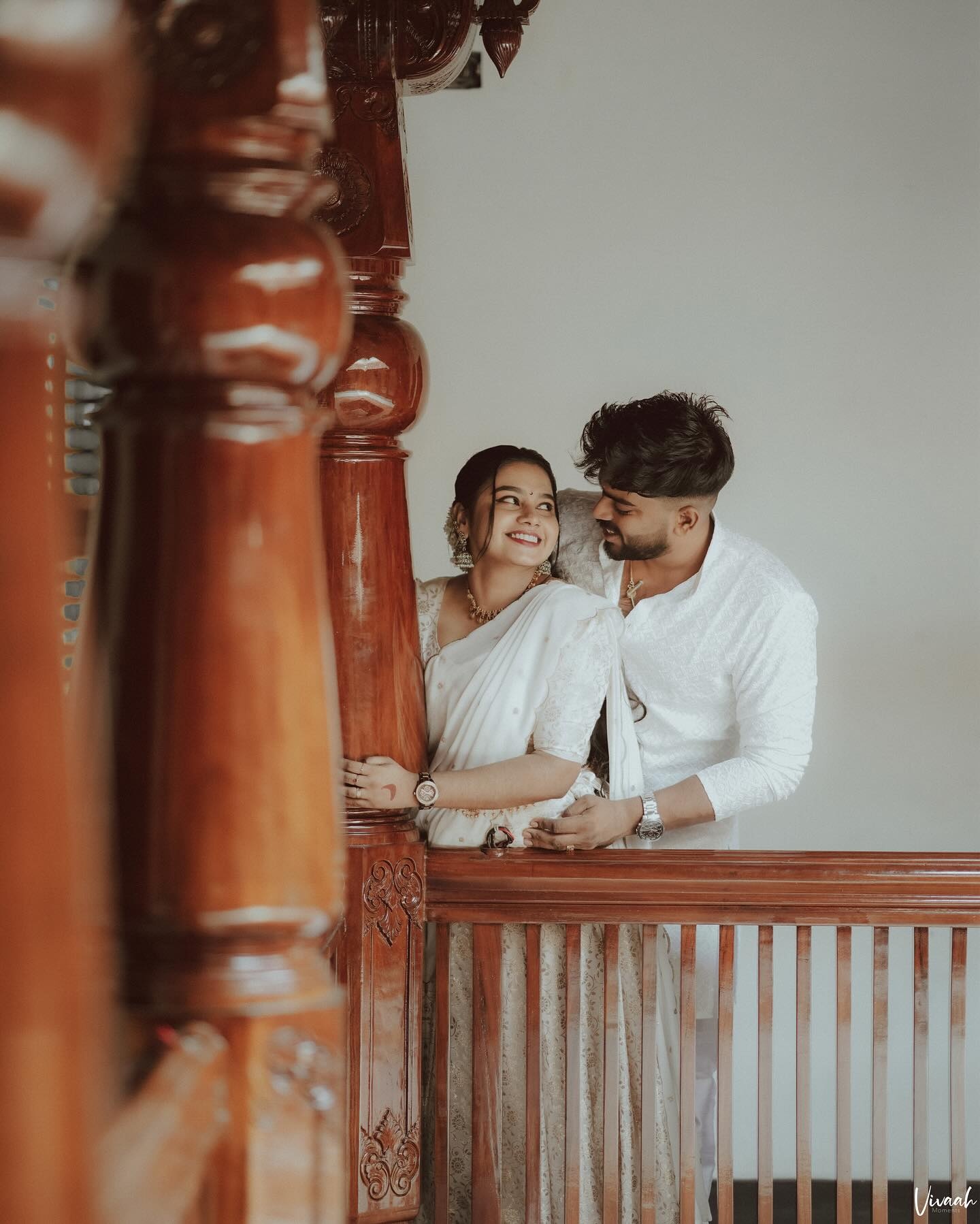 A smiling couple framed by a heritage wooden balcony