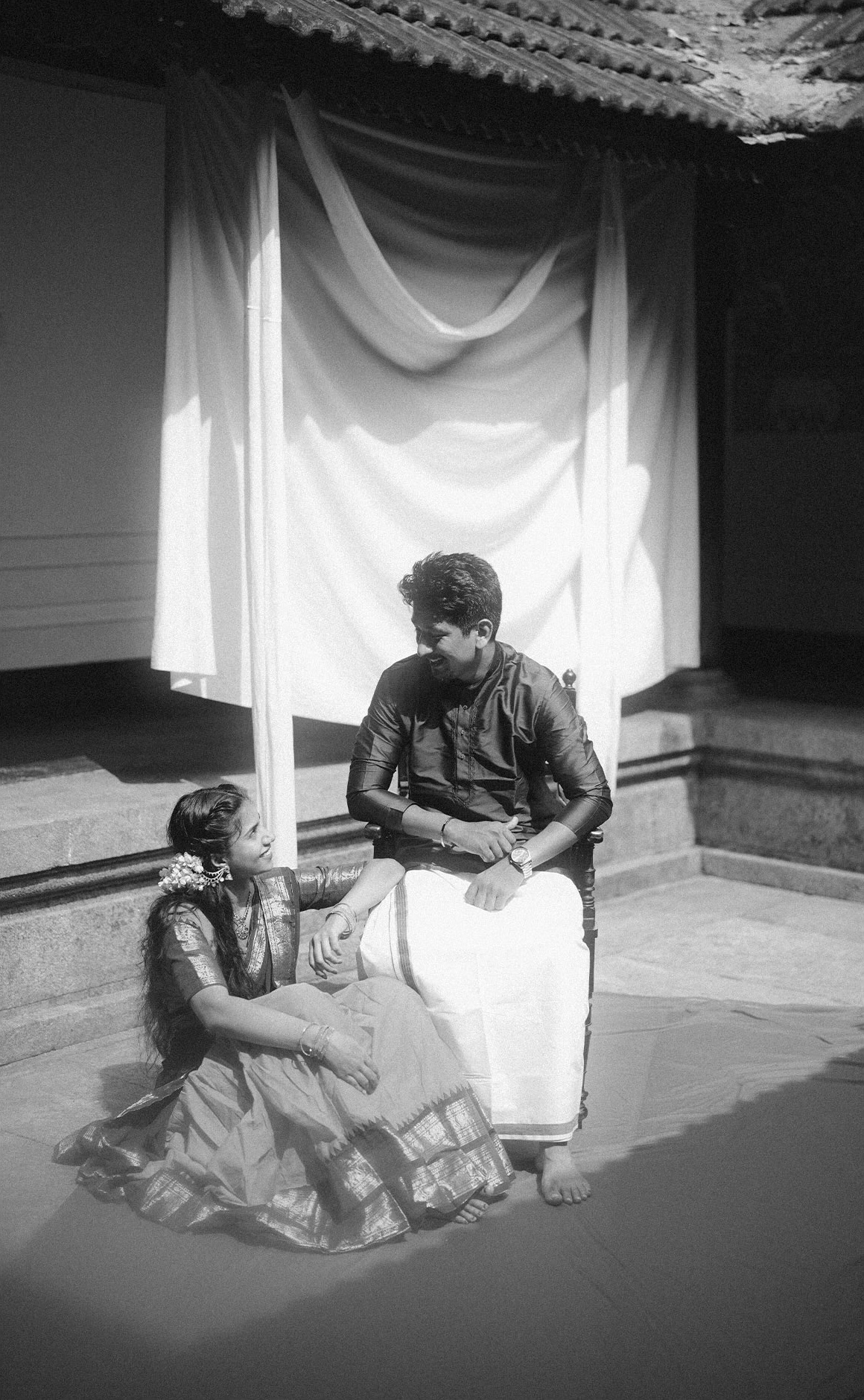 A black-and-white portrait of a couple in a traditional home